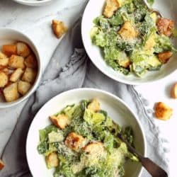 overhead image of 3 bowls of Caesar salad with homemade croutons on a white background
