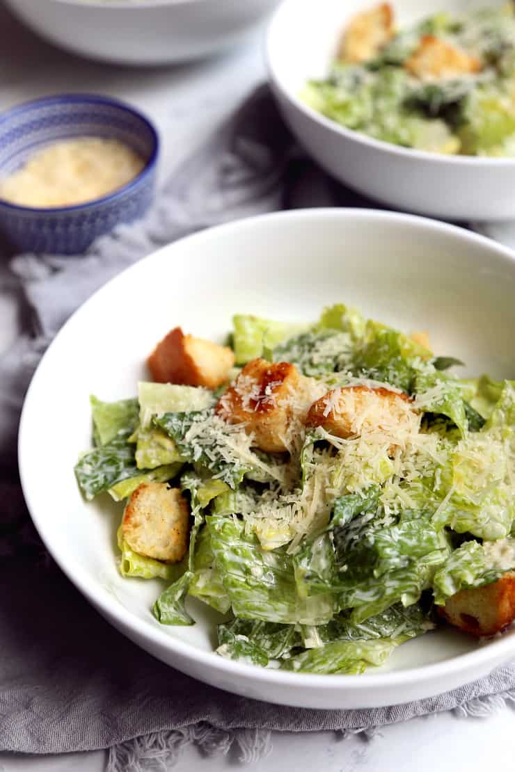 close up view of Caesar salad in bowl on marble background