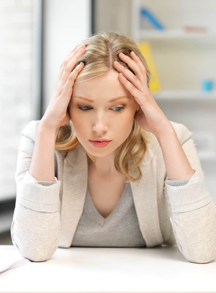 blonde woman feeling stressed at her work desk