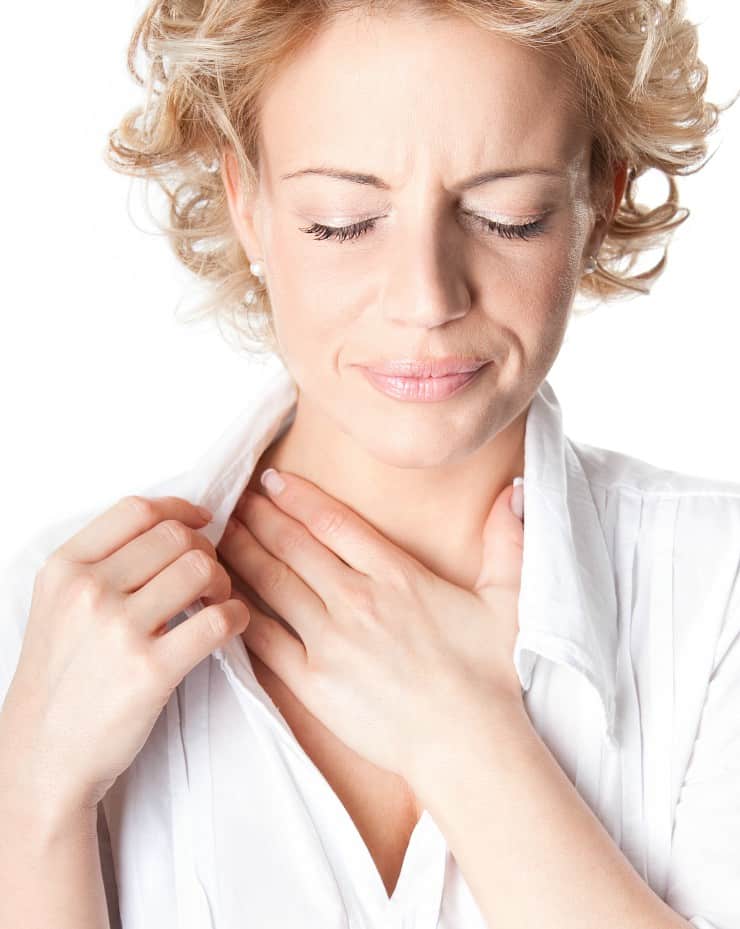 Blonde woman putting hand to her chest with acid reflux pain