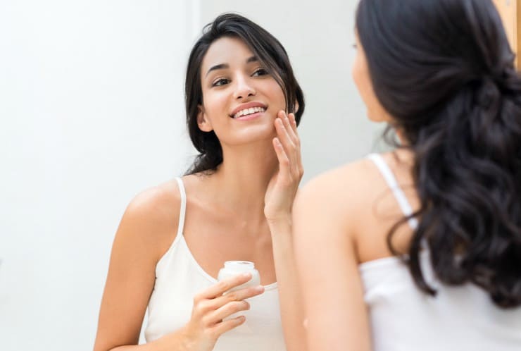 woman applying natural skin cream in mirror