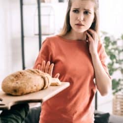 Young woman refusing to eat bread due to gluten sensitivity