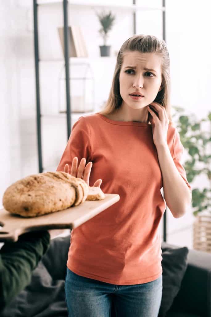 Young woman refusing to eat bread due to gluten sensitivity