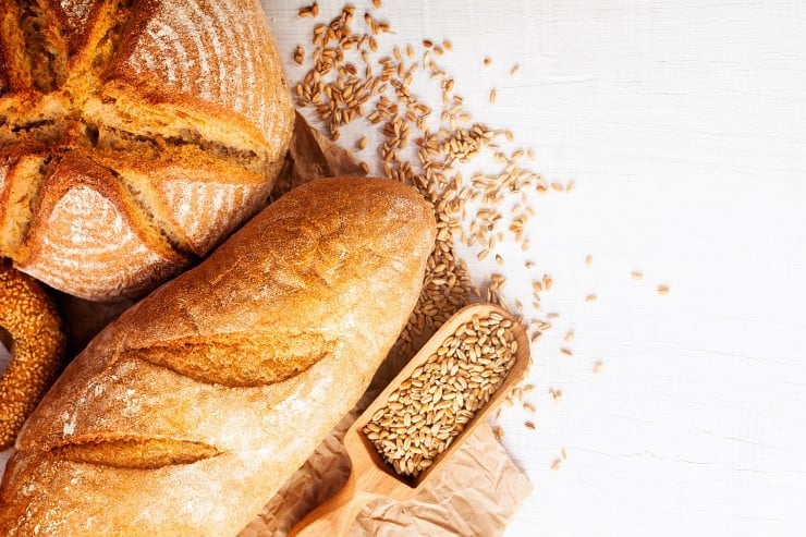 overhead shot of bread products containing gluten on a white background