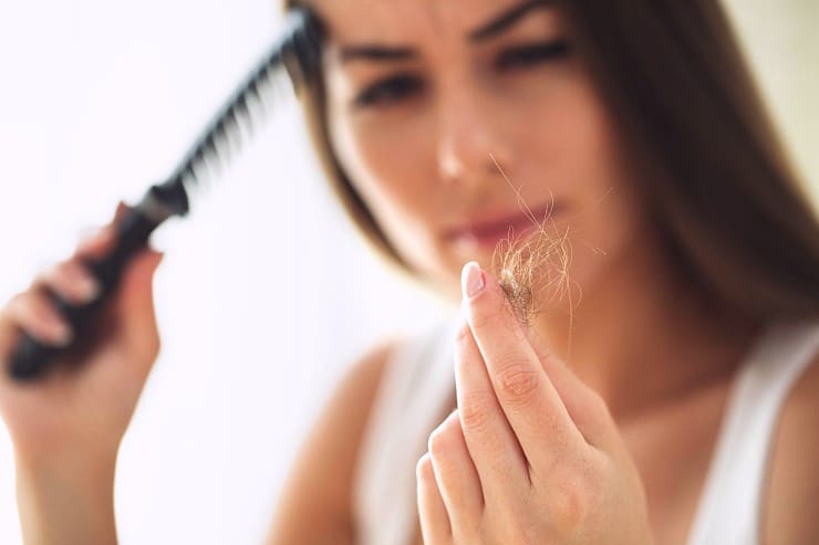 Concerned woman holding clump of hair that fell out