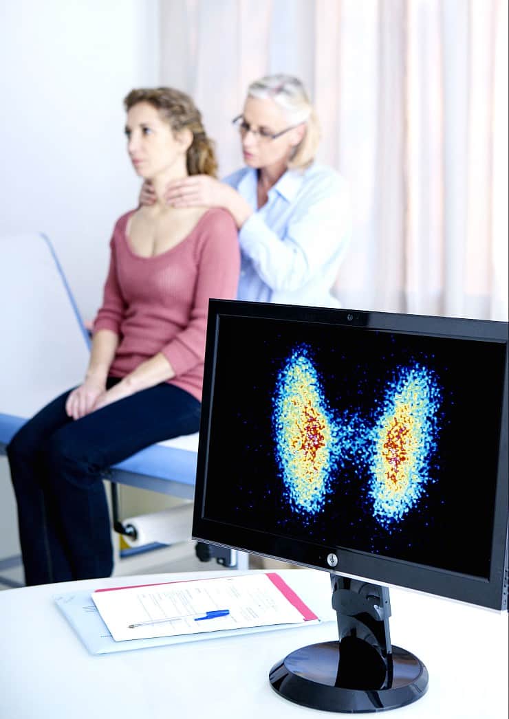 Image of doctor examining a woman's thyroid