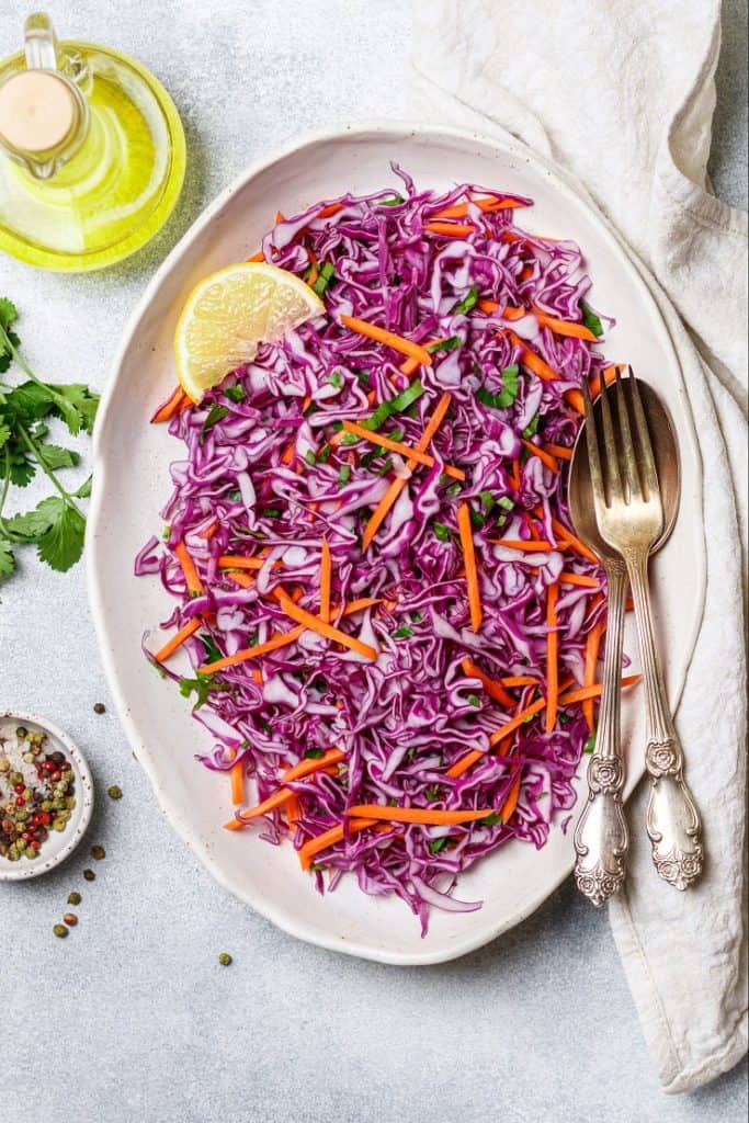 overhead image of purple calbbage and carrot slaw on light gray background