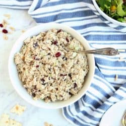 Overhead image of tuna salad in white bowl with blue and white napkin and bowl of salad greens in background