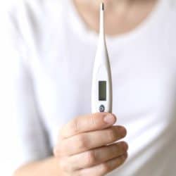 Close up image of woman holding digital thermometer