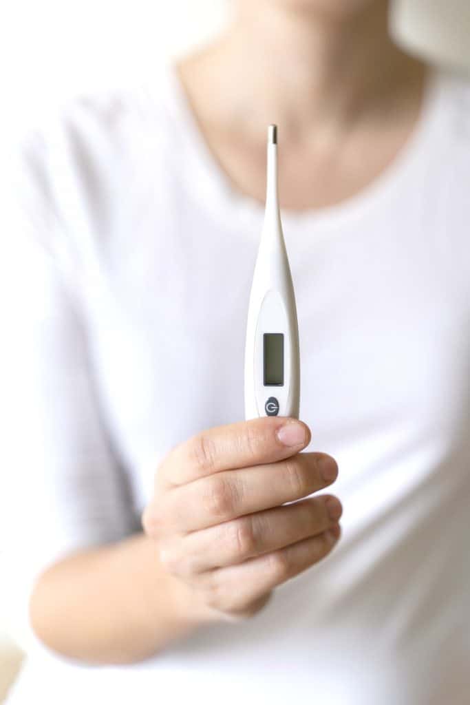 Close up image of woman holding digital thermometer
