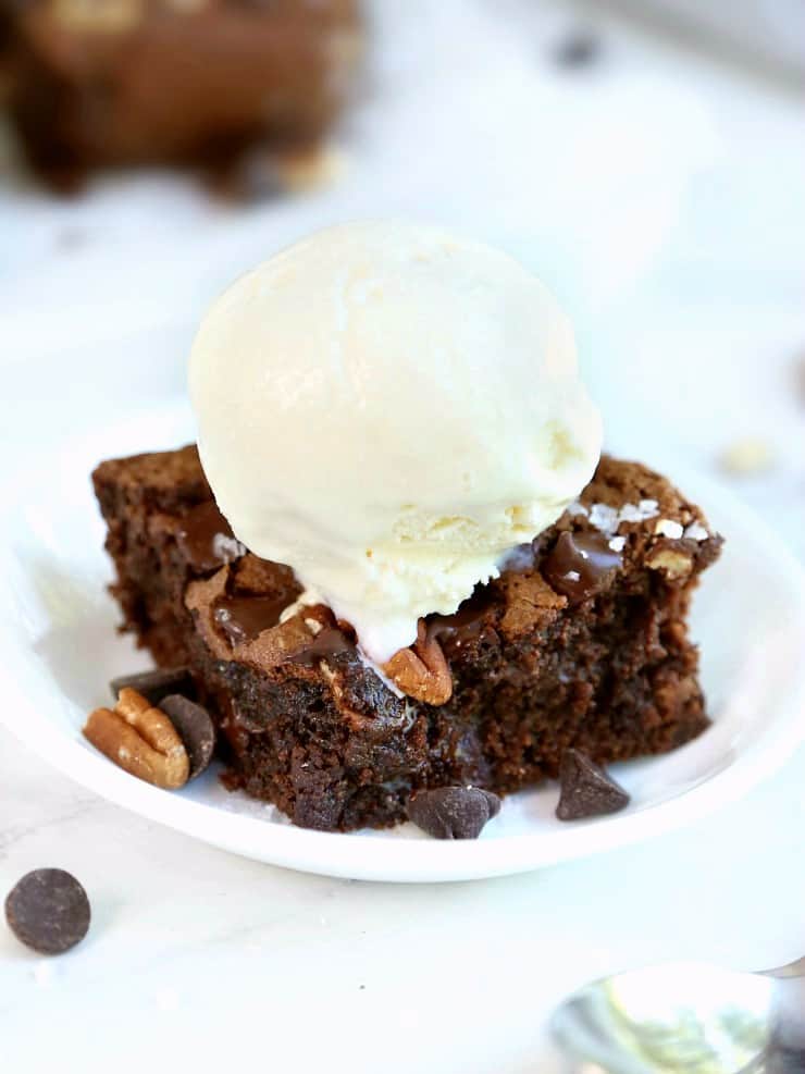 front view of fudgy flourless brownie with dark chocolate and sea salt, topped with scoop of ice cream