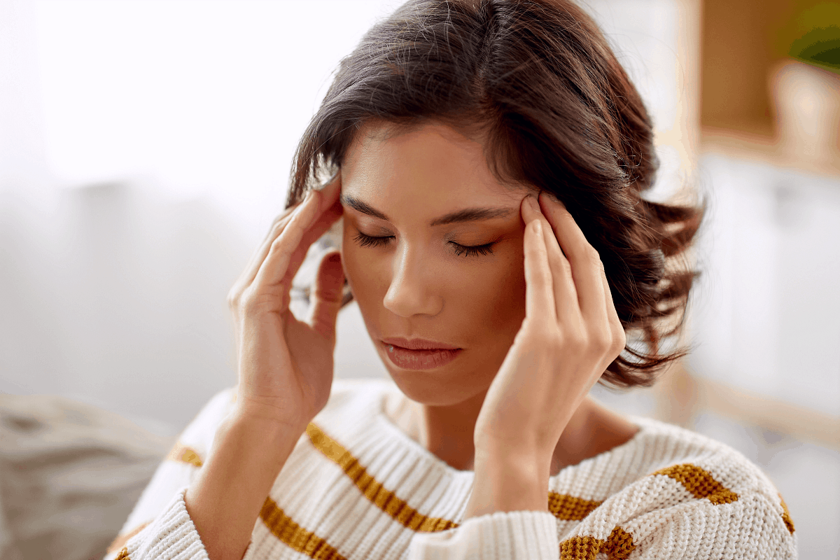 Stressed out woman closing eyes and pressing fingers to her temples 