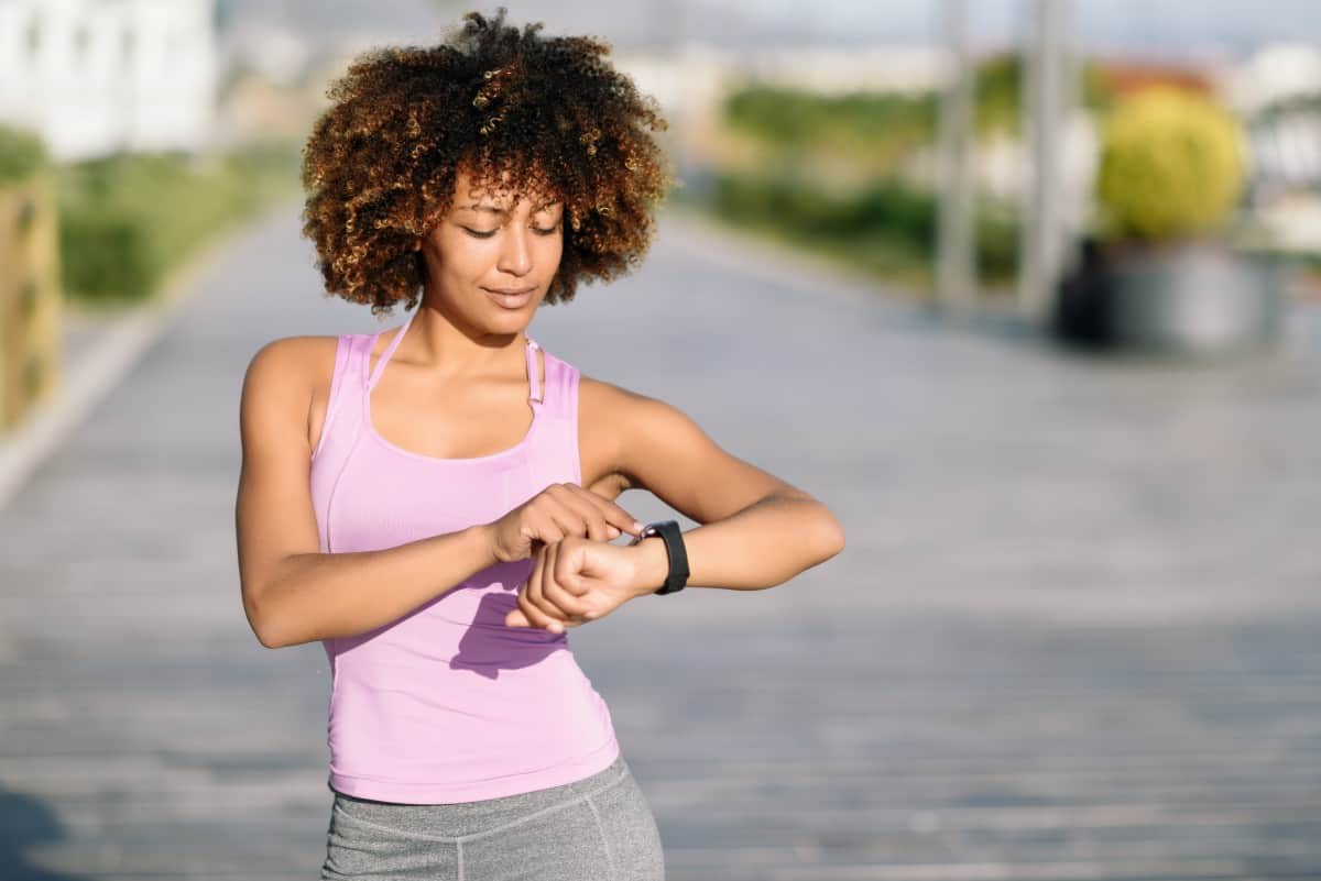 Black woman out jogging on city street, stopped to check her time