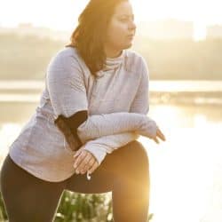 Brunette woman stretching on bench in middle of her morning run