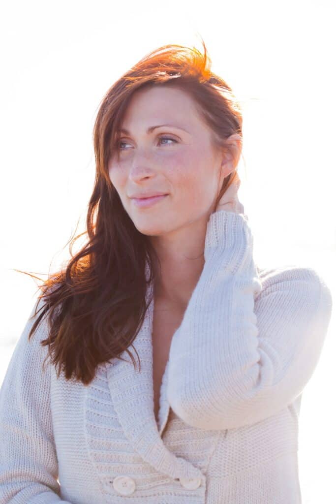 Peaceful red headed woman in white sweater outside gazing off into the distance