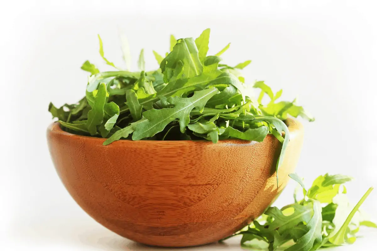 close up image of wooden bowl of arugula leaves to help raise stomach acid