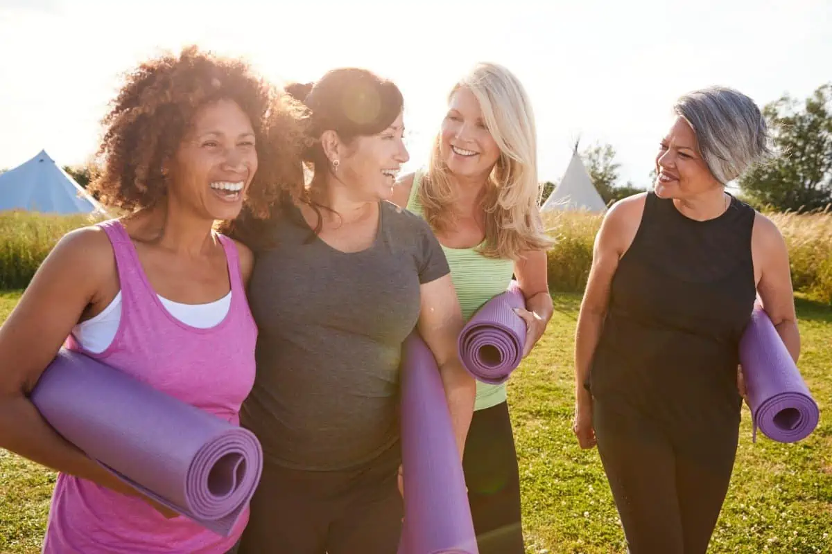 4 mid life women walking with their yoga mats and laughing