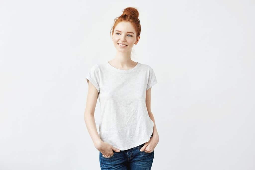 Thin young woman with red hair wearing jeans and t shirt, smiling