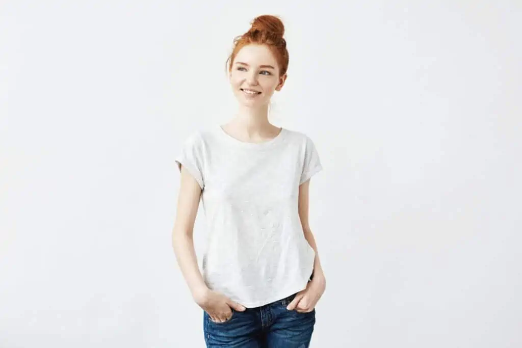 Thin young woman with red hair wearing jeans and t shirt, smiling